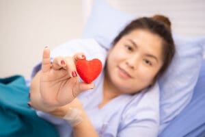 Patients of Size in medical bed holding a heart.